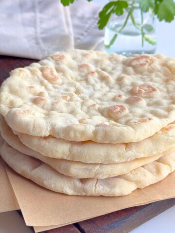 Soft no yeast stovetop pita bread stacked on a wooden board