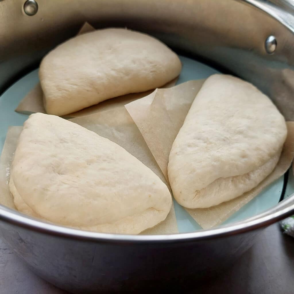 Pick up the buns with the parchment paper still under it and place into the steamer. 