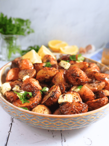 Easy Garlic And Lemon Roast Potatoes - Greek-Style served in a bowl with feta and olives
