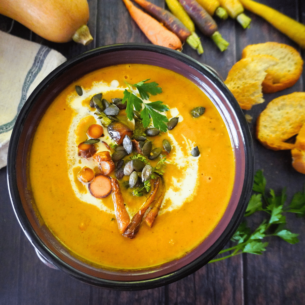 This roasted butternut squash and carrot soup combines sweet vegetables, fresh herbs, rich cream, and a hint of chili spice, all topped with crunchy pumpkin seeds