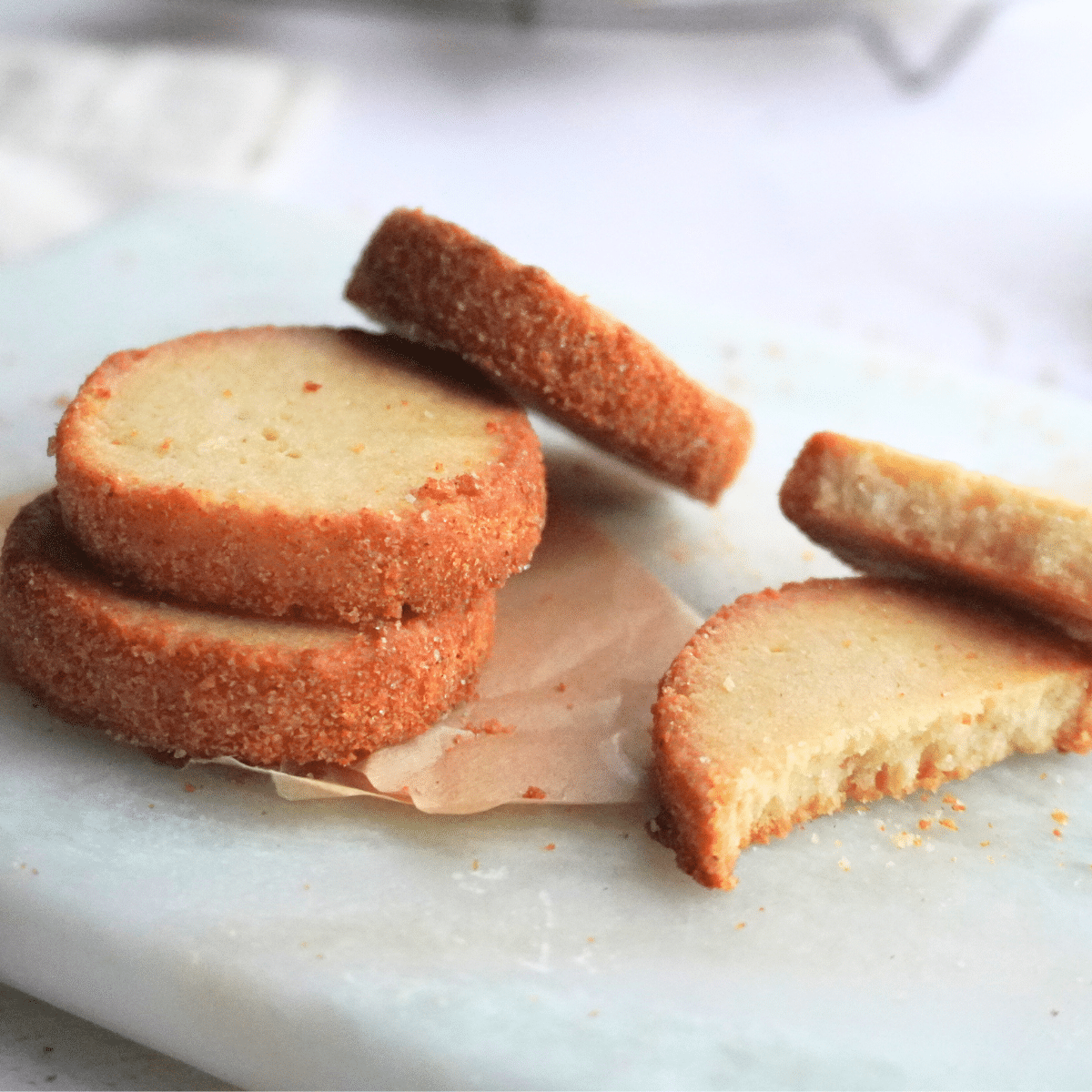 Sour cream butter cookies on a plate with one broken in half to show the soft, crumbly texture inside.