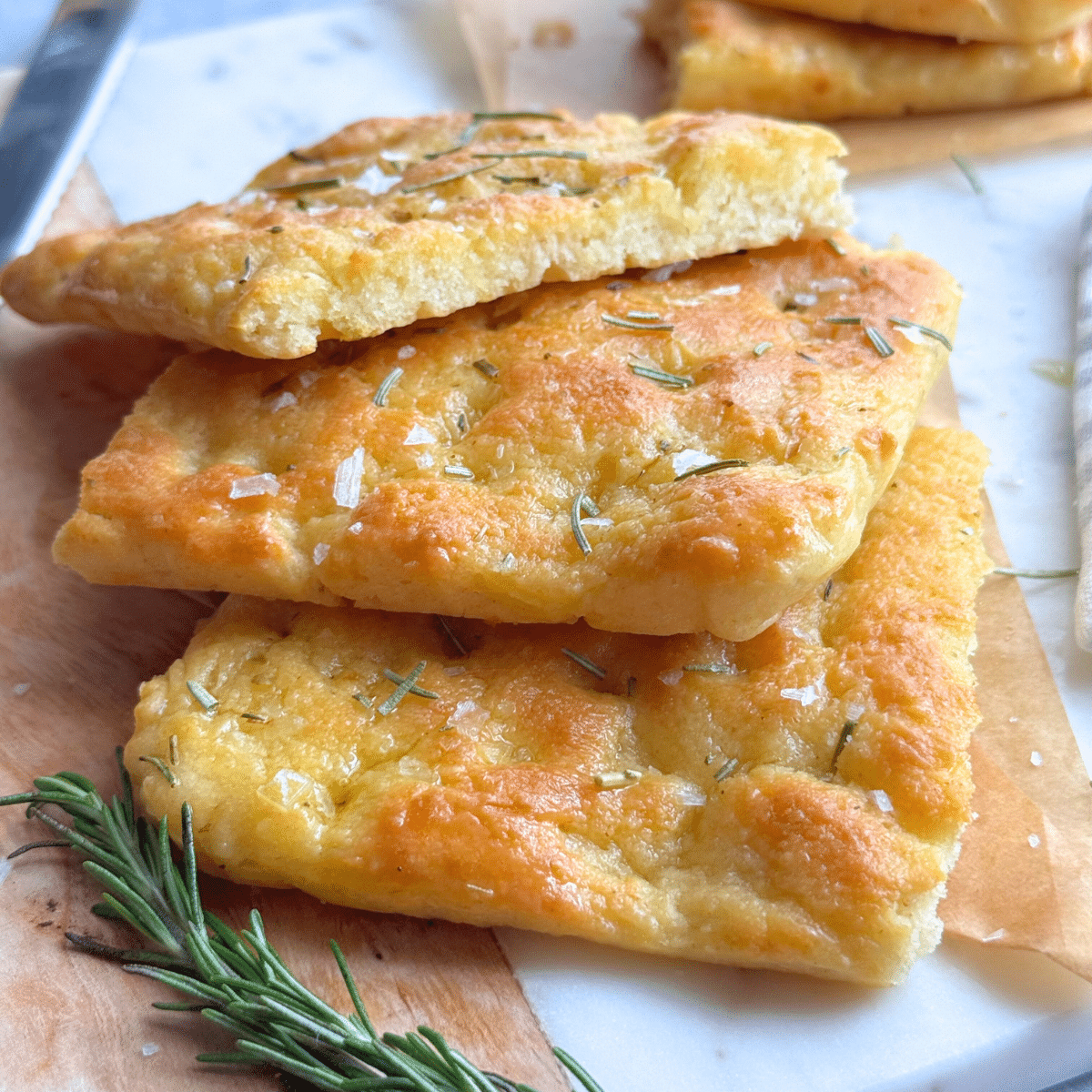 Close-up of no-yeast focaccia slices showing golden crisp crust and fluffy interior, topped with flaky salt and rosemary
