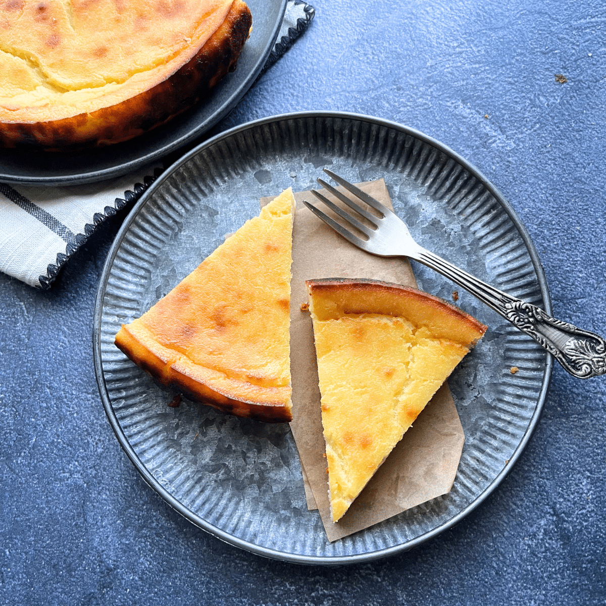 two slices of lemon ricotta cake on a metal plate with a vintage fork, served on parchment paper