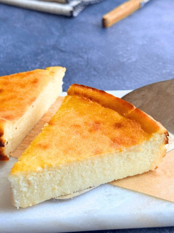 Slice of lemon ricotta semolina cake with a soft, creamy center and golden top, served on a marble board.