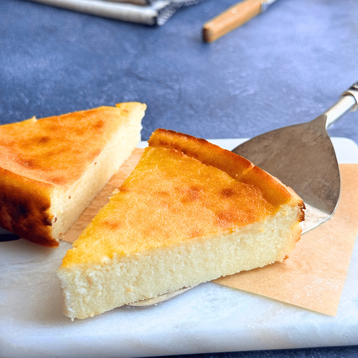 Slice of lemon ricotta semolina cake with a soft, creamy center and golden top, served on a marble board.