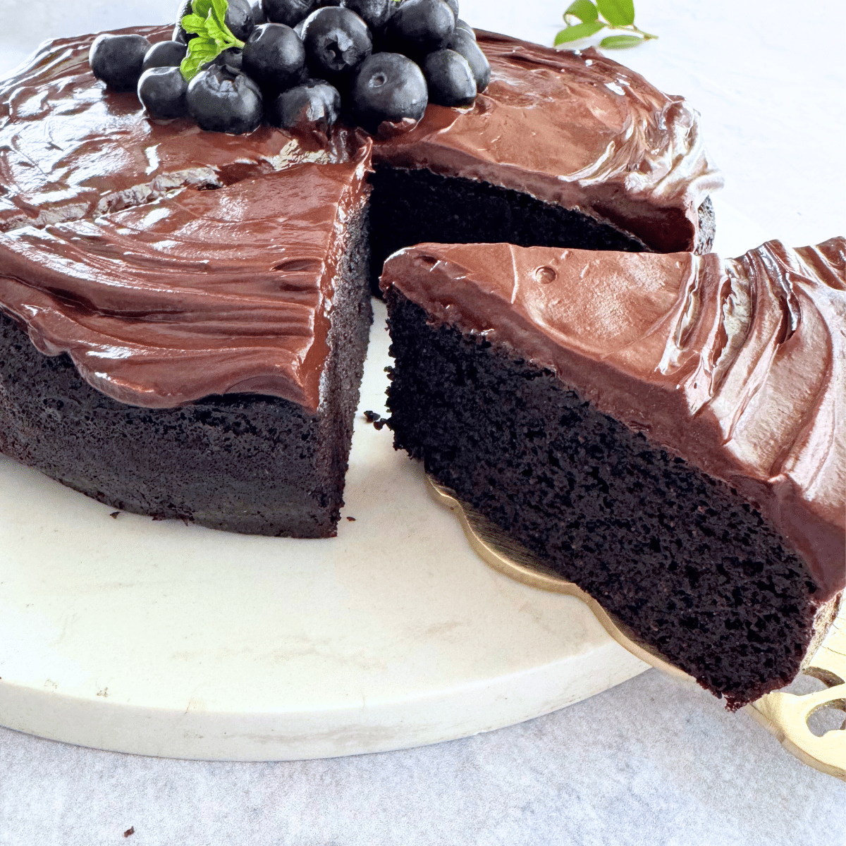 soft almond flour chocolate cake with a rich chocolate topping and blueberries in the center.