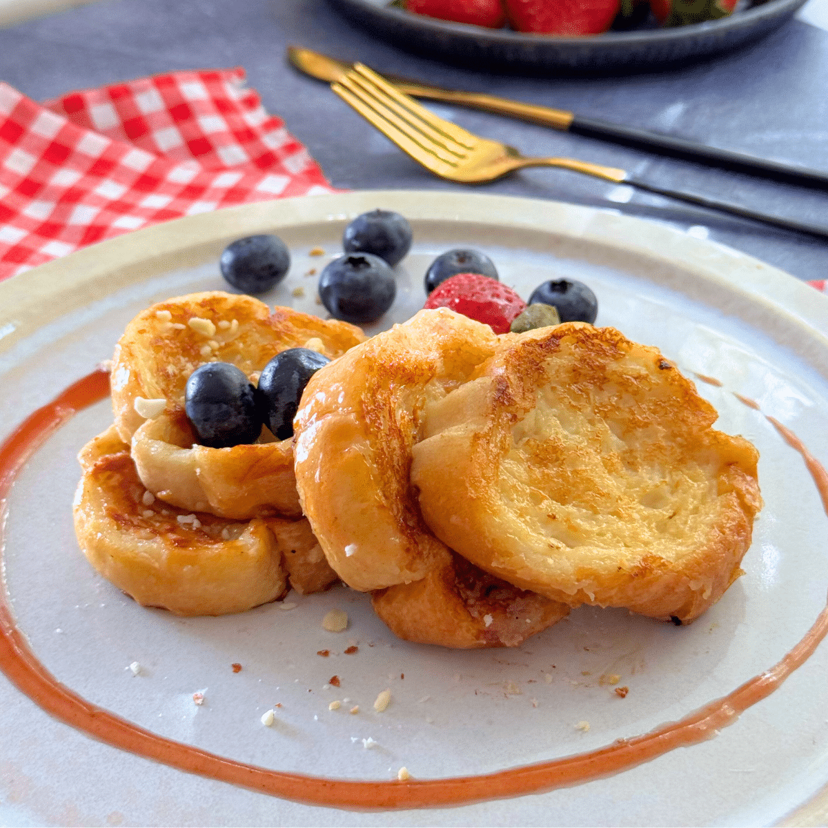 Close-up of mini French toast rounds made with melted ice cream, served with blueberries and strawberries on a white plate.