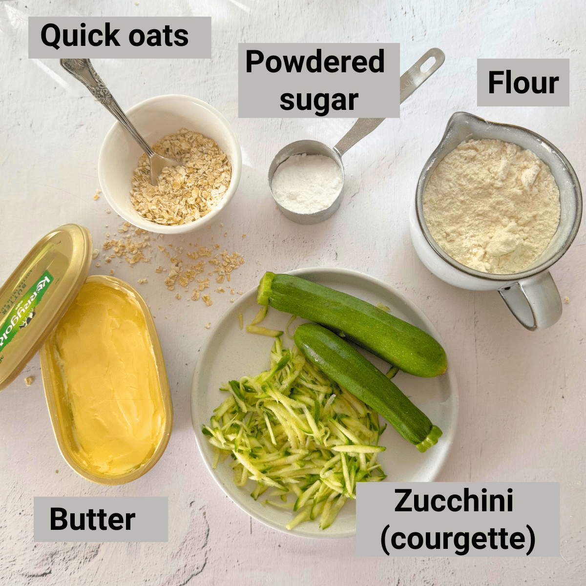 Flat lay of ingredients for zucchini butter cookies: grated zucchini, butter, quick oats, powdered sugar, and all-purpose flour