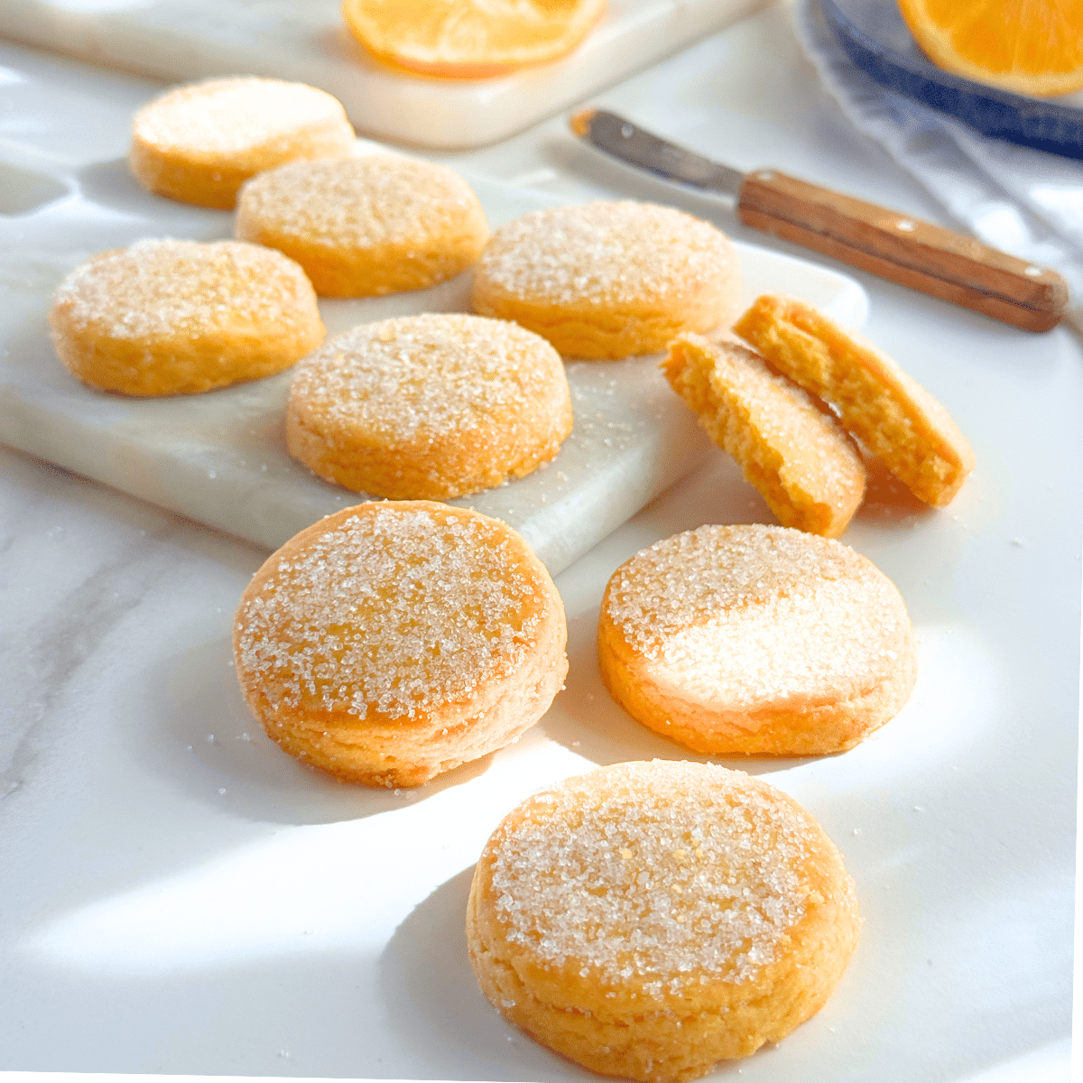 Golden orange butter cookies on marble board, one sliced open to show soft interior
