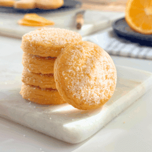 Stack of orange butter cookies coated in sugar, glowing softly in natural light