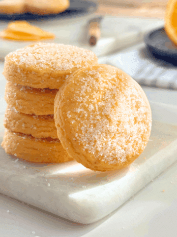 Stack of orange butter cookies coated in sugar, glowing softly in natural light