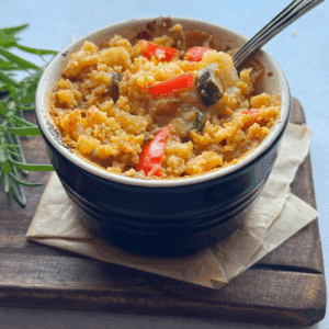 Creamy vegetable casserole with crispy topping in ramekin with spoon