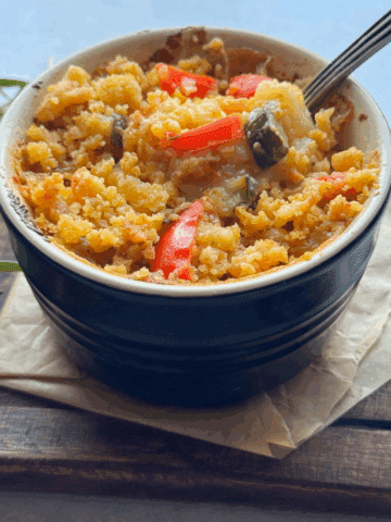 Creamy vegetable casserole with crispy topping in ramekin with spoon
