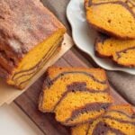 Slices of pumpkin marble cake with chocolate swirls on a wooden board and plate.