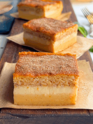 Pumpkin custard cake sliced to show 3 layers and served on parchment placed on board