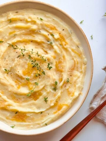 Top view of French onion mashed potatoes swirled with caramelized onions and garnished with fresh thyme.