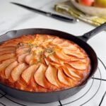 Golden pear cake baked in a cast-iron skillet, topped with caramelized pear slices and fresh thyme.