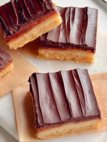 No-bake millionaire’s shortbread bars with defined chocolate, caramel, and shortbread layers arranged on parchment paper