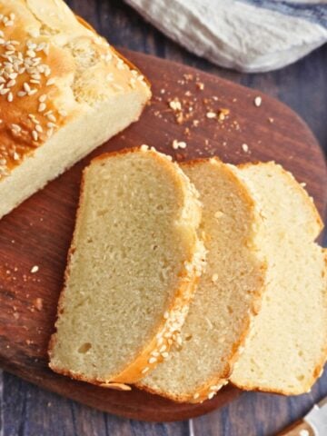 Sliced no-yeast quick bread with a golden top and sesame seeds on a wooden board