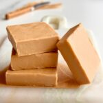 Stacked pieces of smooth 2-ingredient Biscoff fudge made with white chocolate on a marble board.