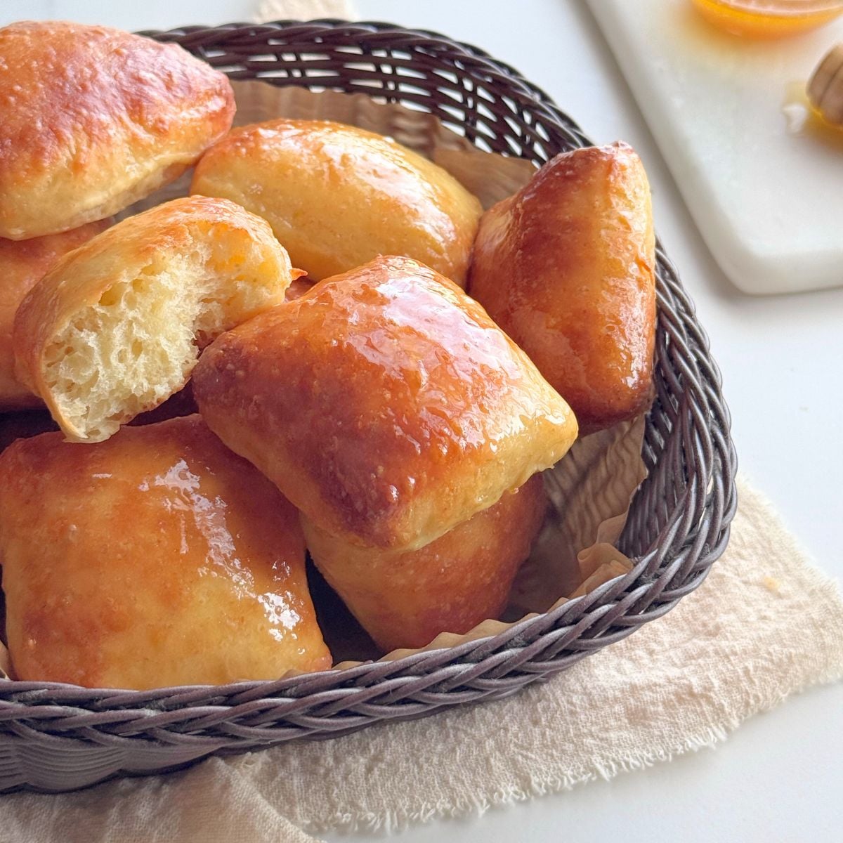 Soft no-knead honey butter dinner rolls brushed with honey butter, served in a basket