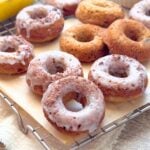 Glazed baked banana chocolate chunk donuts on a cooling rack with parchment paper.