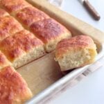 No-knead buttermilk pull-apart rolls baked in a pan with one roll pulled apart to show the soft crumb.