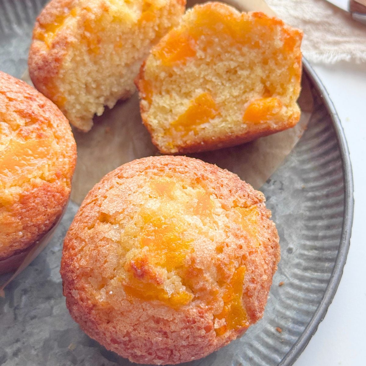 Peach muffin cut in half to show the soft interior and diced peaches.